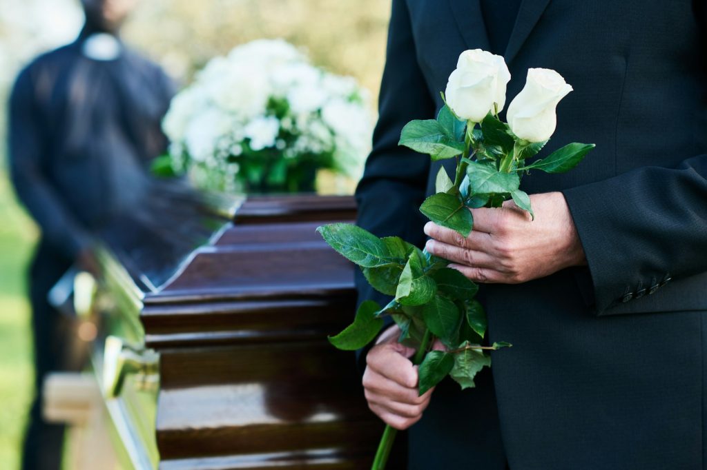 Close-up of matue man in black suit holding two fresh white roses